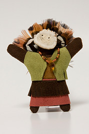 a small doll-like fetish with a headdress of feathers, beaded necklace, mask and dress made of leather.